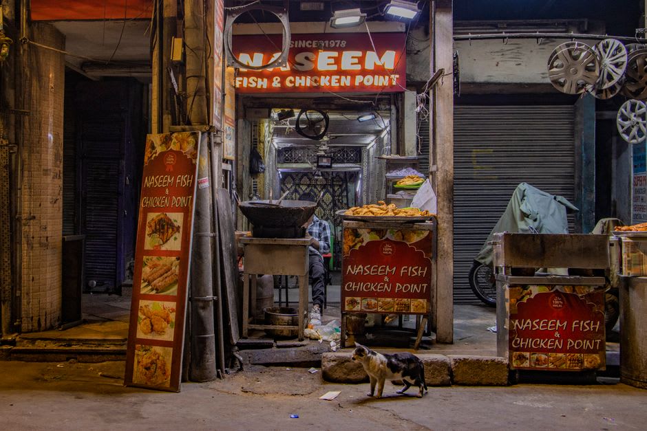 A crowded night food market stall grilling pav bhaji in Ahmedabad's Manek Chowk
