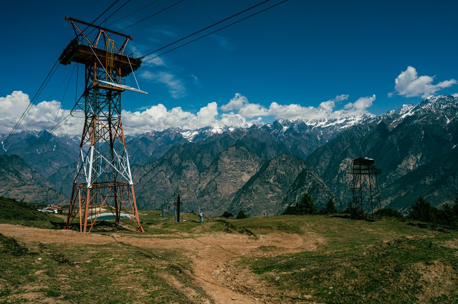 The Auli cable car gliding over pine forest toward the ski slopes and snow peaks above
