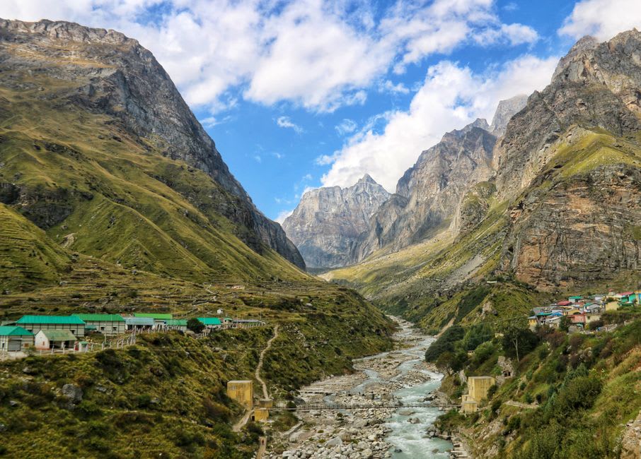 Mana village's stone houses with the Bhim Pul rock bridge and river visible nearby