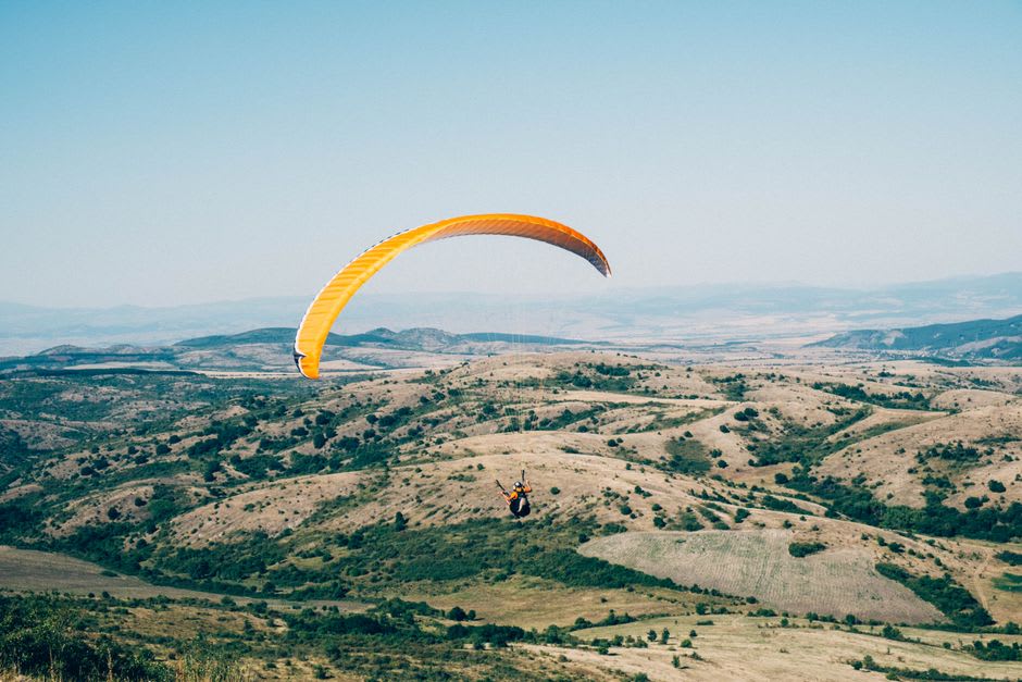 A paraglider soaring above the terraced fields of the Kangra valley near Bir Billing