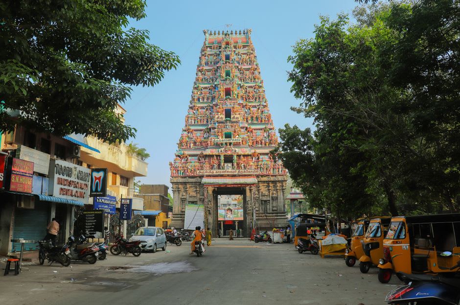Illuminated gopuram of Kapaleeshwarar Temple with oil lamps burning around the temple tank at dusk