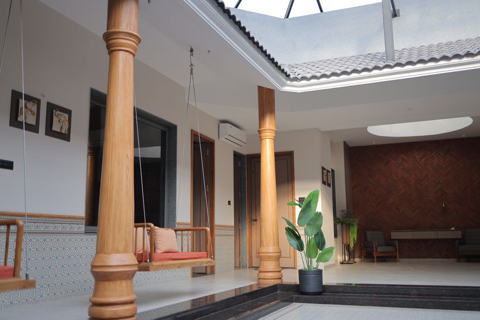 A vast, empty courtyard inside a Chettinad mansion with tall teak pillars and patterned tile flooring