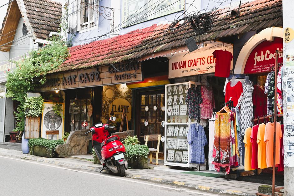 Quiet Hassan street at dusk with shopfronts, motorbikes, and strings of jasmine for sale