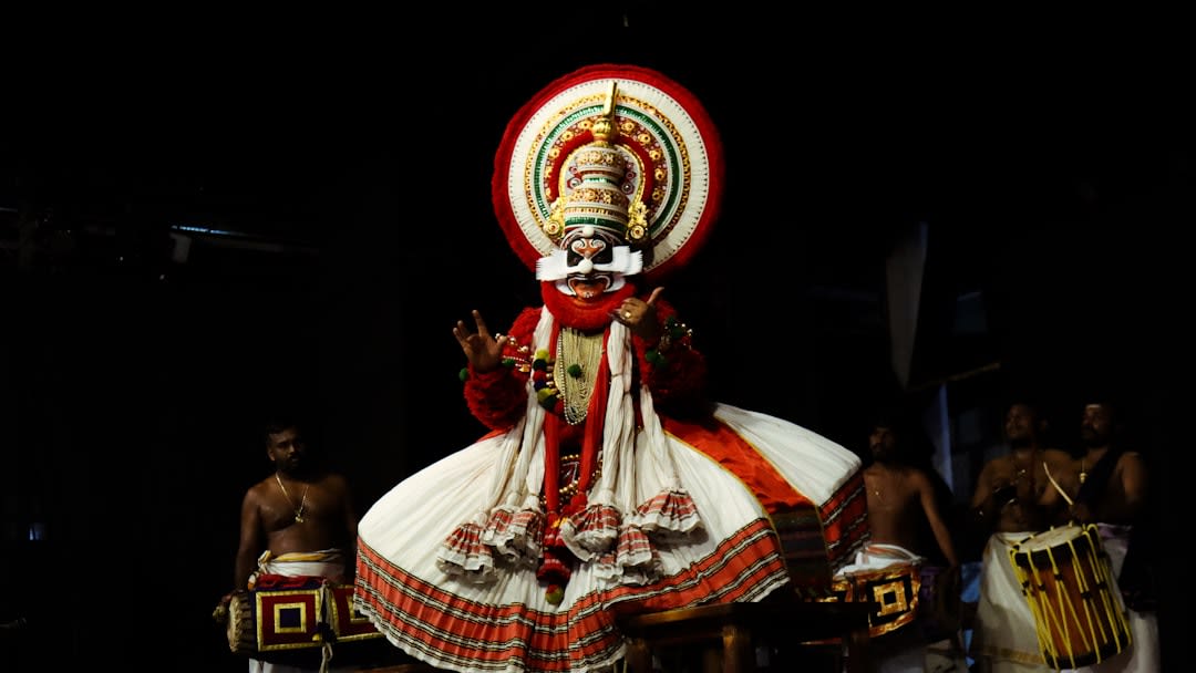 A Kathakali performer applying elaborate green and red facial makeup before a performance in Kochi