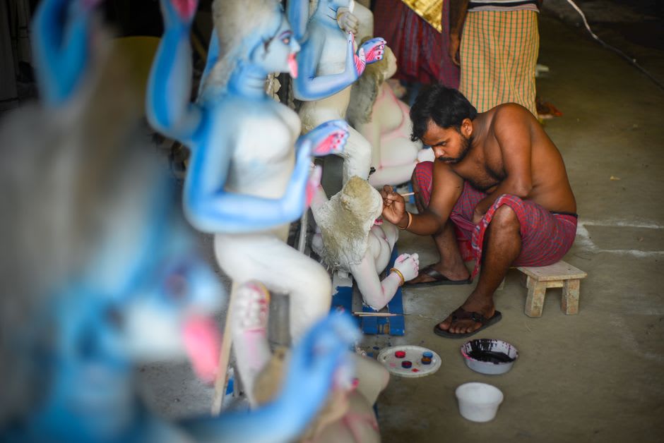 A narrow blue-painted street in Mathura lined with shops selling Krishna idols