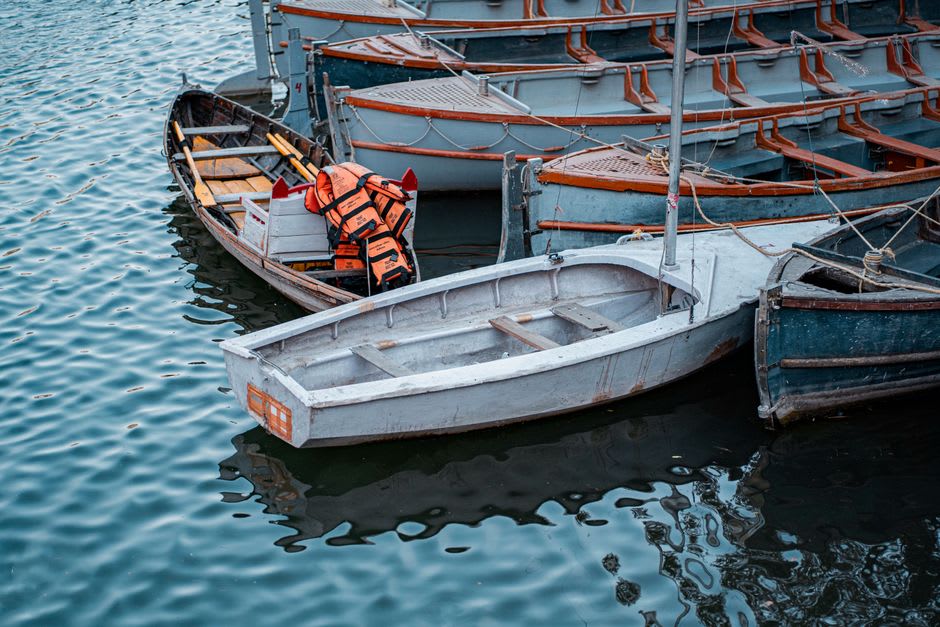 Rowboats crossing the still green waters of Naini Lake in the early morning