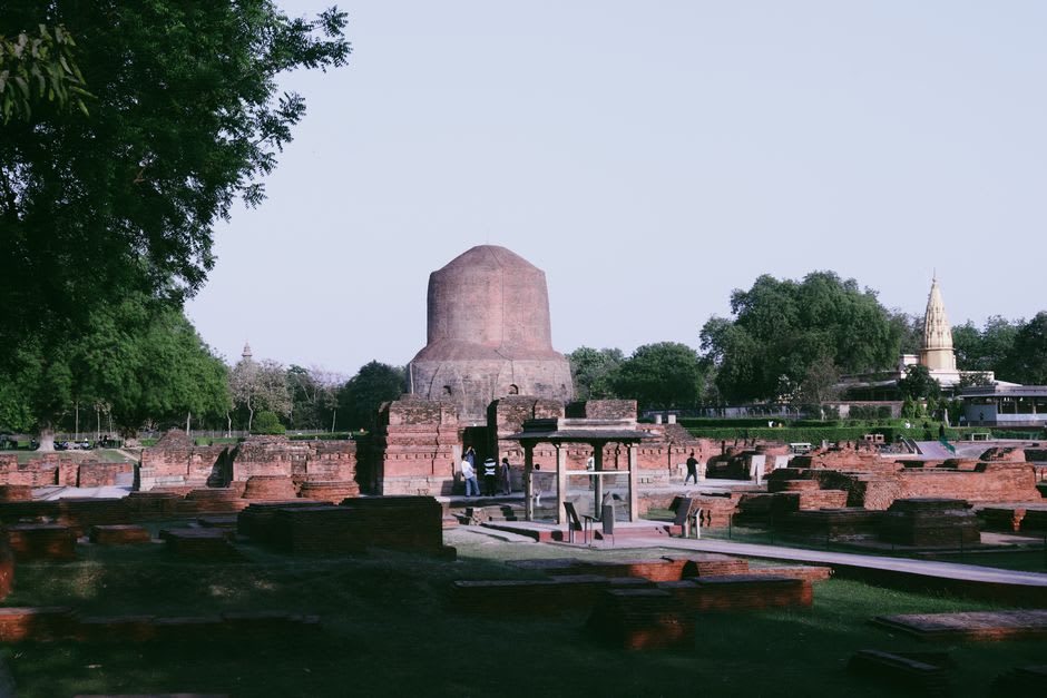 Pilgrims in saffron and maroon robes circling the Dhamek Stupa at Sarnath