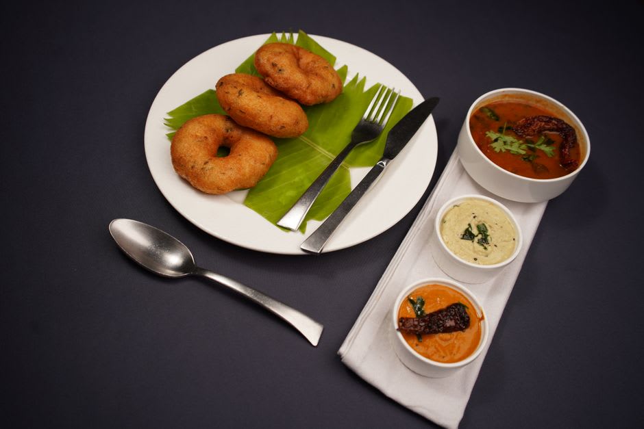 Communal banana-leaf meal being served with sambar and rice in an Udupi temple hotel