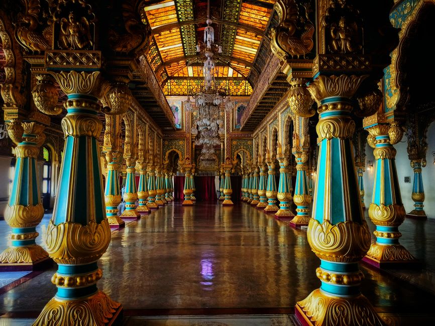 The mosaic-tiled durbar hall interior of Laxmi Vilas Palace lit by stained glass