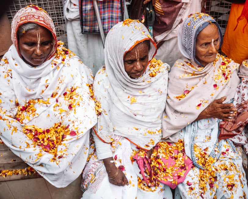 Widows in white saris singing devotional bhajans inside a Vrindavan ashram hall