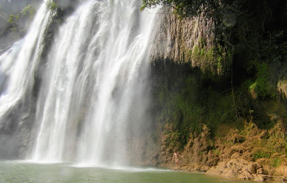 Waterfall dropping from a granite cliff face into a jungle pool in Harau Valley