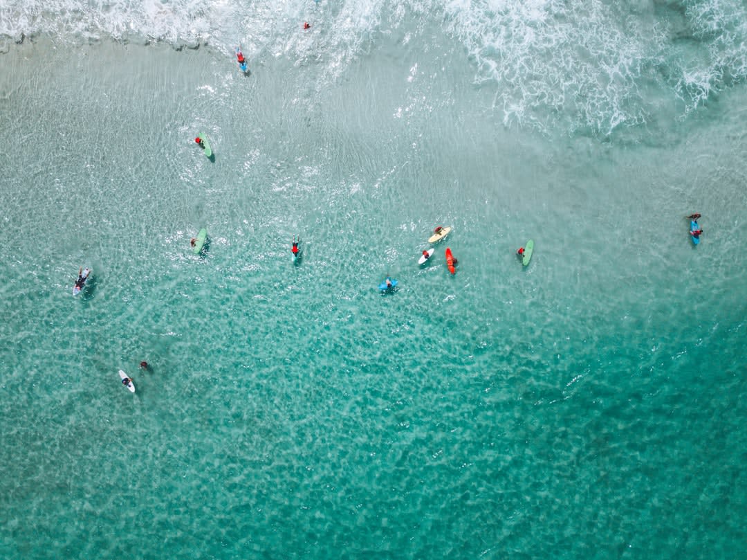 Surfers paddling out toward a barreling wave at Plengkung, Java