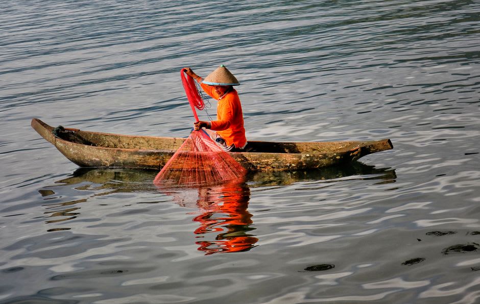 Traditional wooden fishing boats on Danau Singkarak at dawn with nets strung along the shore