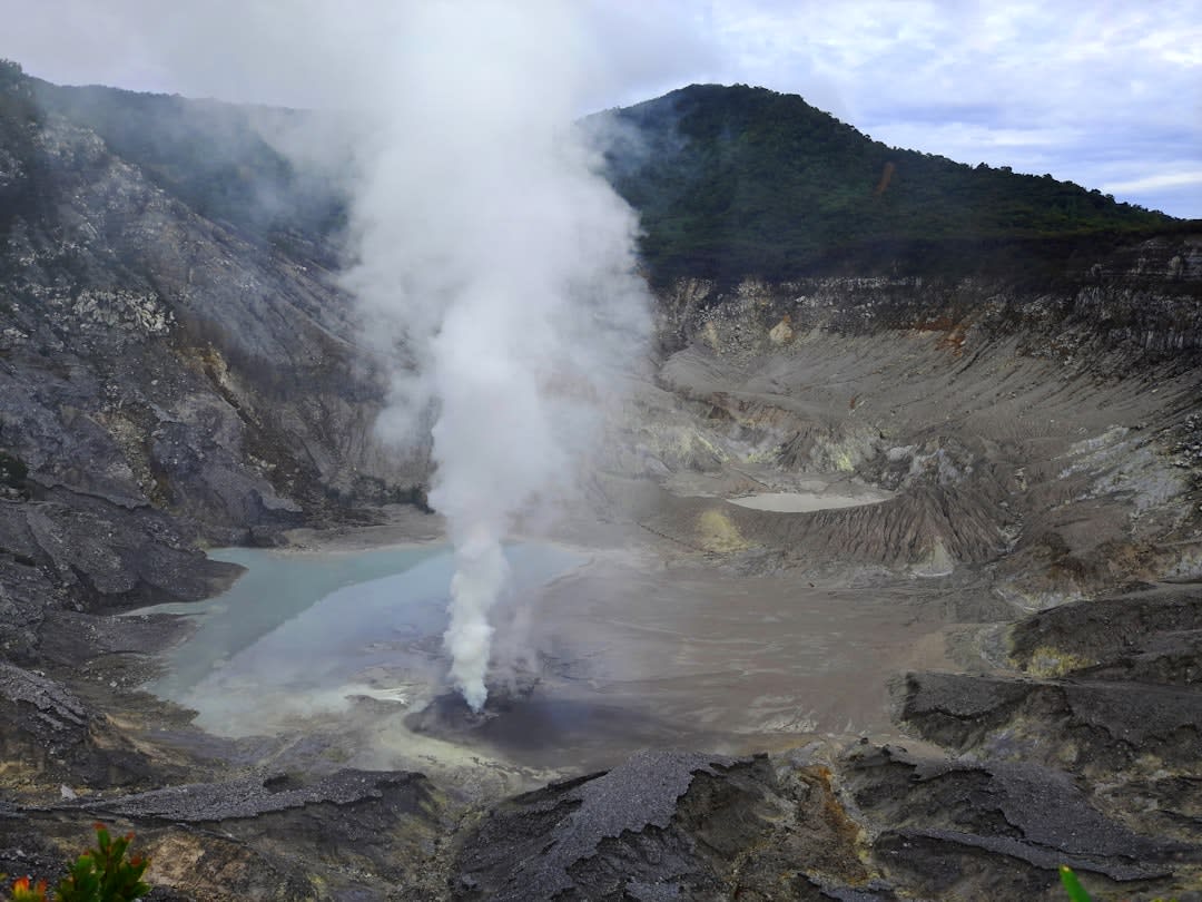 Steam and sulfur rising from the bubbling mud pools of Kawah Sikidang crater on Dieng Plateau
