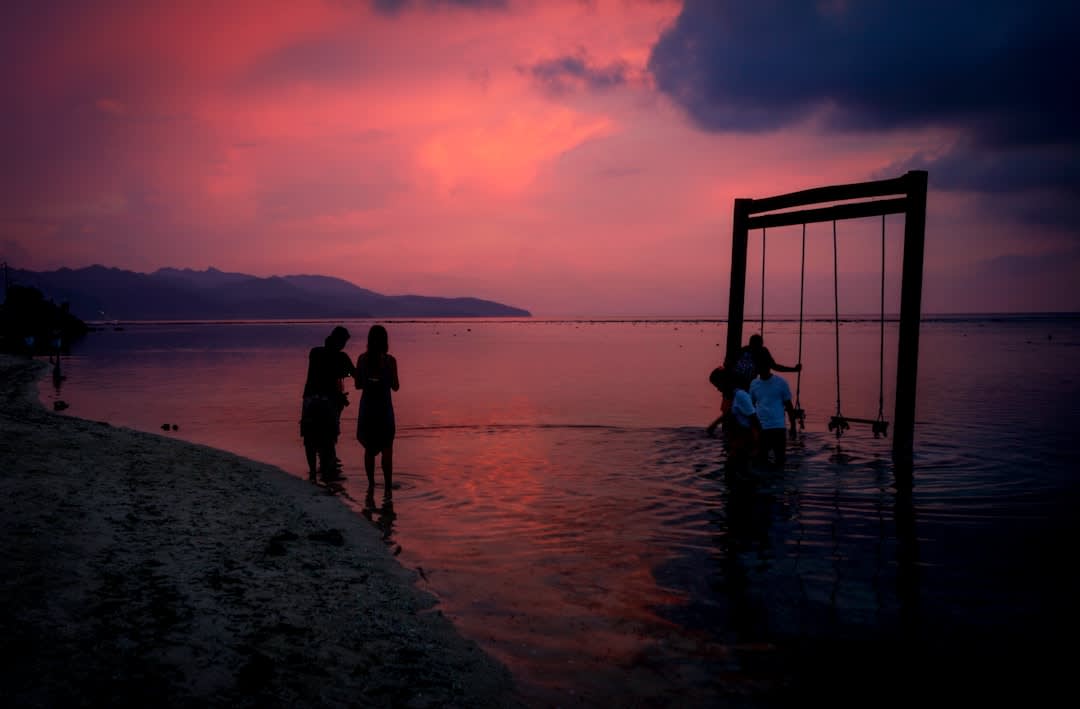Sunset silhouette of a swing on the beach with Bali's Mount Agung on the horizon