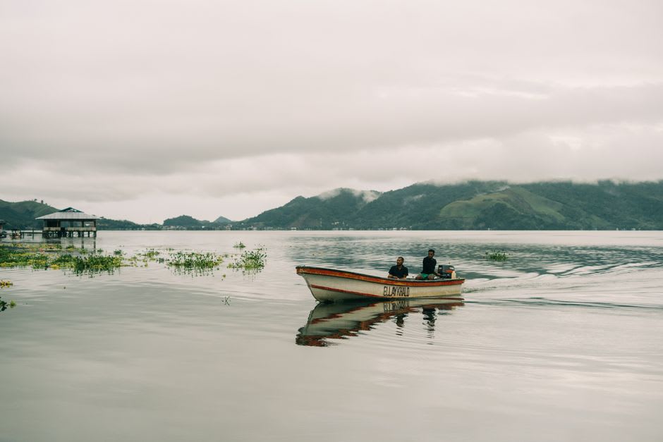 Stilt houses and dugout canoes on Lake Sentani with the Cyclops Mountains behind