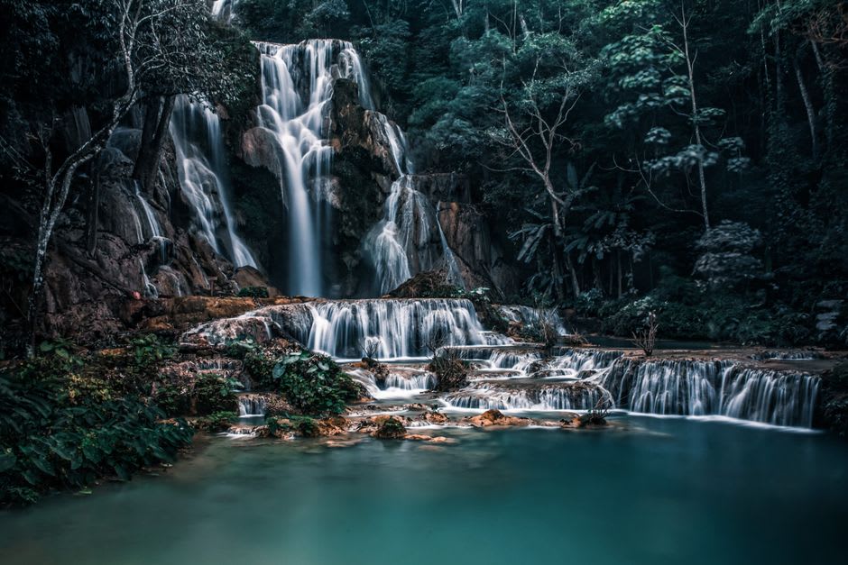 A waterfall cascading through dense tropical forest into a clear pool