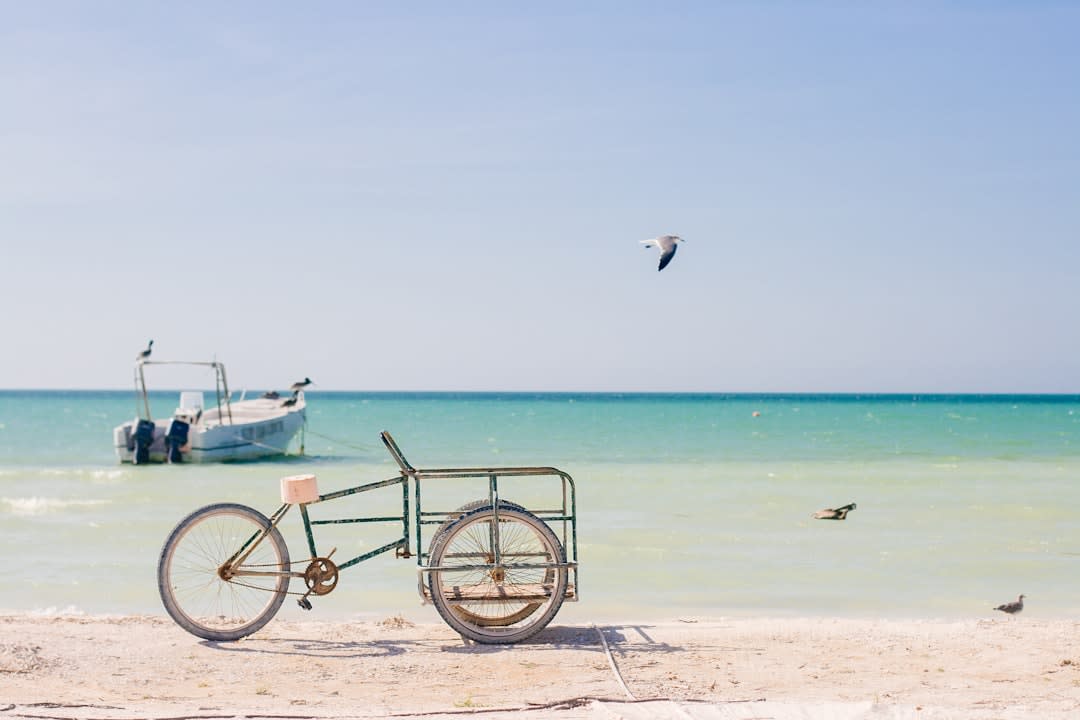 A wooden fishing boat pulled up on a white-sand beach with turquoise water