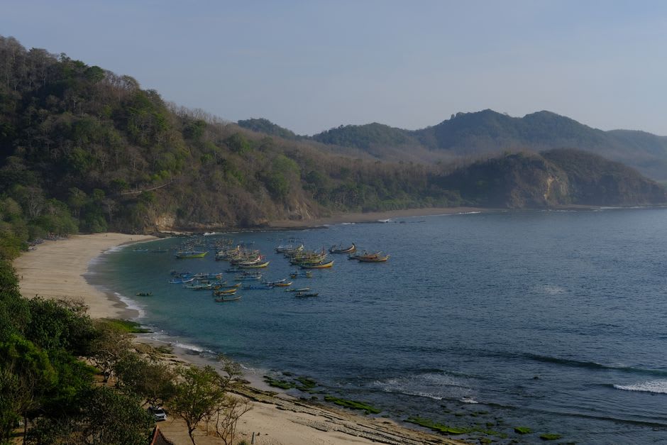 A quiet beach cove on Pulau Weh with wooden fishing boats and green hills behind