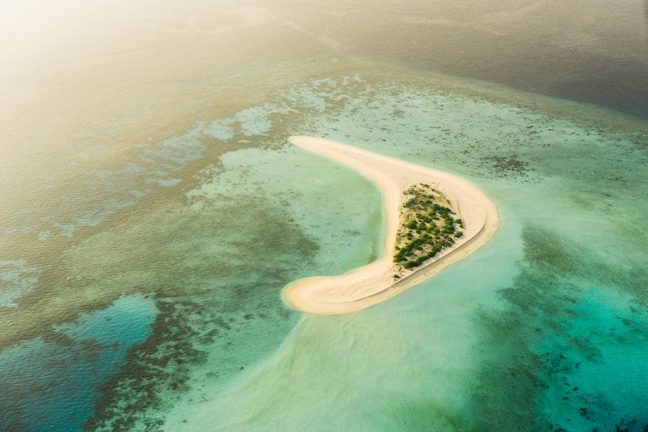 An expansive coral atoll with scattered sandy islets visible from above