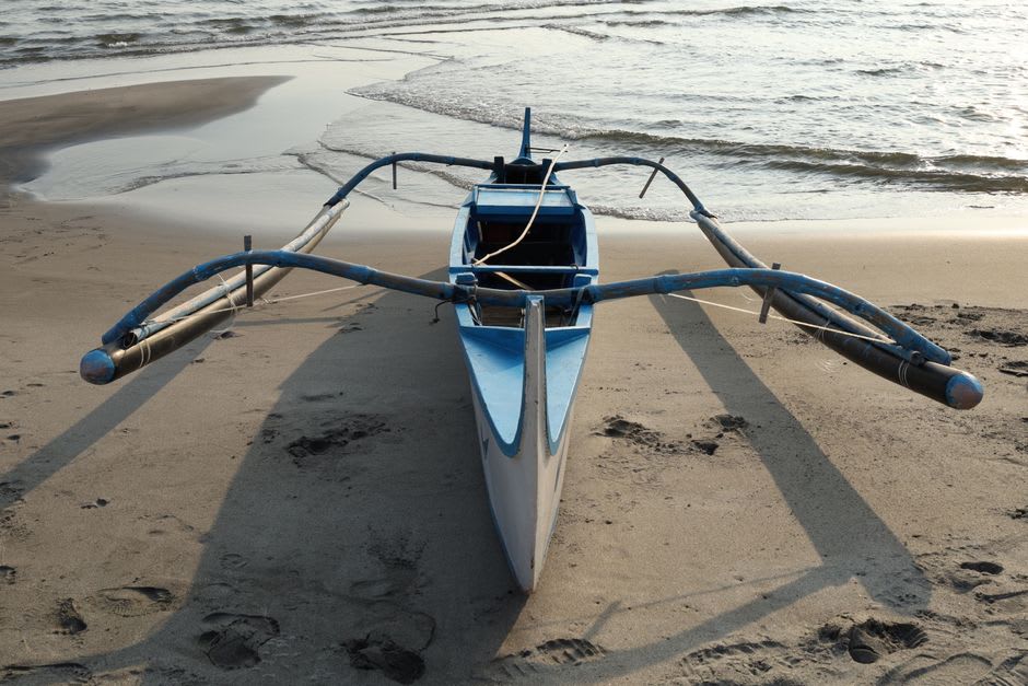 Traditional jukung outrigger canoes on the beach at dawn before the crowds arrive