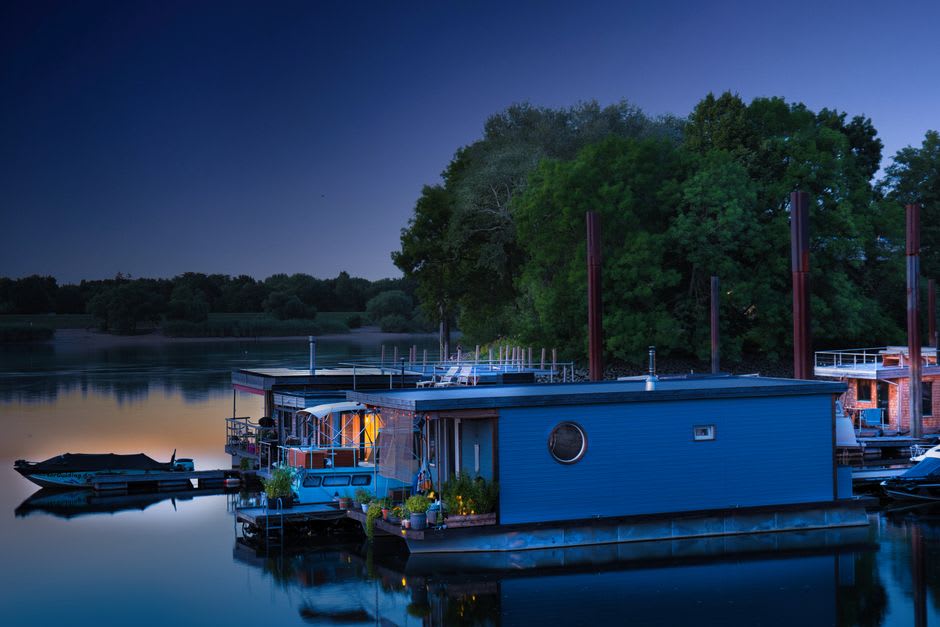 A wooden klotok houseboat moored on the Sekonyer River at dusk with mist rising off the water