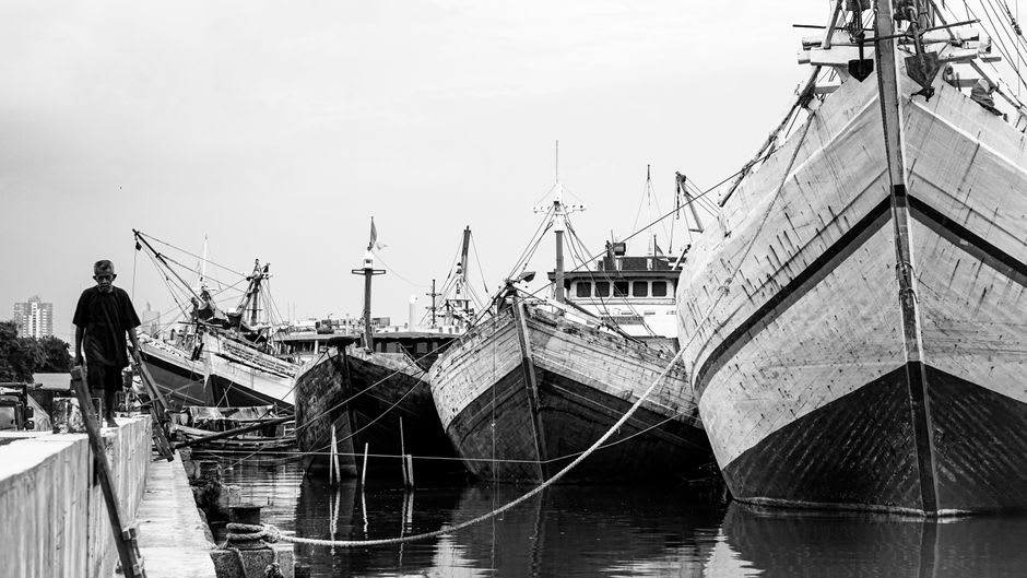 Sunset over Jakarta Bay near Sunda Kelapa with old wooden pinisi schooners docked