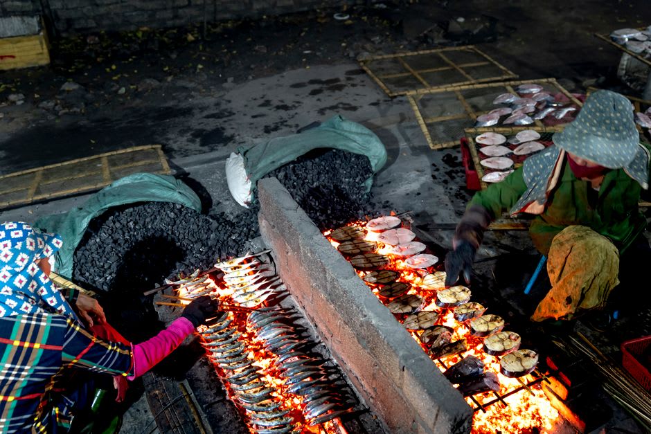 Street food stalls with grilled seafood and steam rising at night in Medan