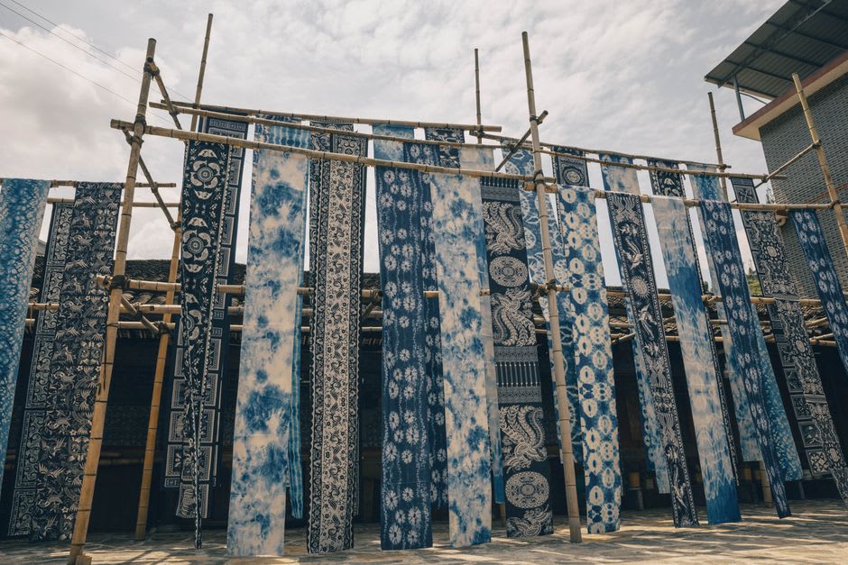 Colorful batik fabric hanging to dry between bamboo poles in a Pekalongan courtyard