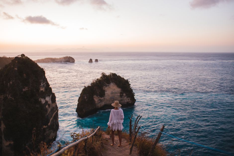 Sunrise light over calm turquoise water with Nusa Penida visible on the horizon
