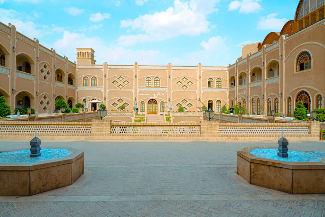 The dense honeycombed muqarnas ceiling above the entrance portal of the Chaharbagh School, tiled in gold and turquoise