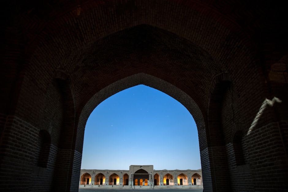 A row of traditional seminary buildings in Qom with students walking between classes