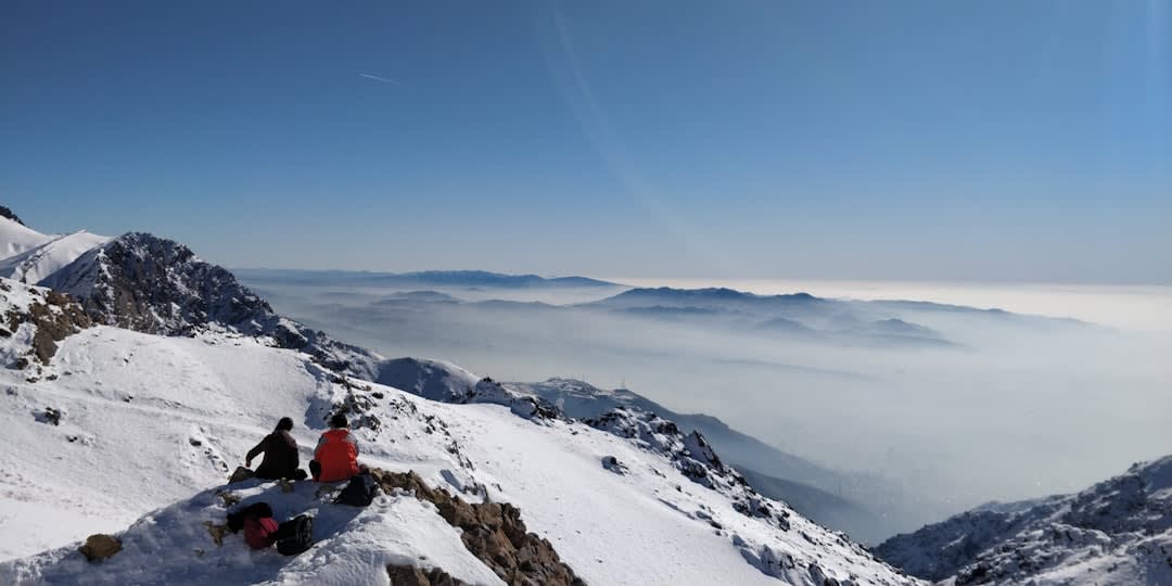 Hikers on a rocky alpine trail near Tochal's upper gondola stations, with distant peaks visible