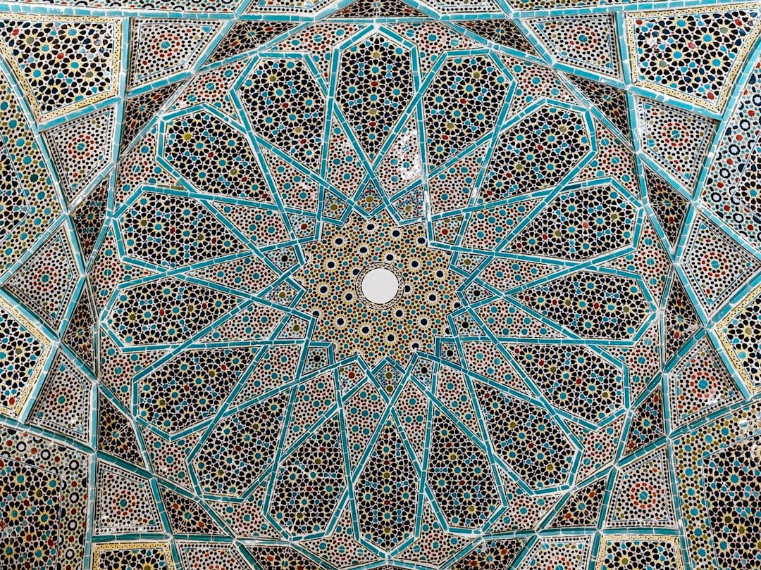 The marble tomb of Hafez under its tiled dome, with visitors reading poetry nearby
