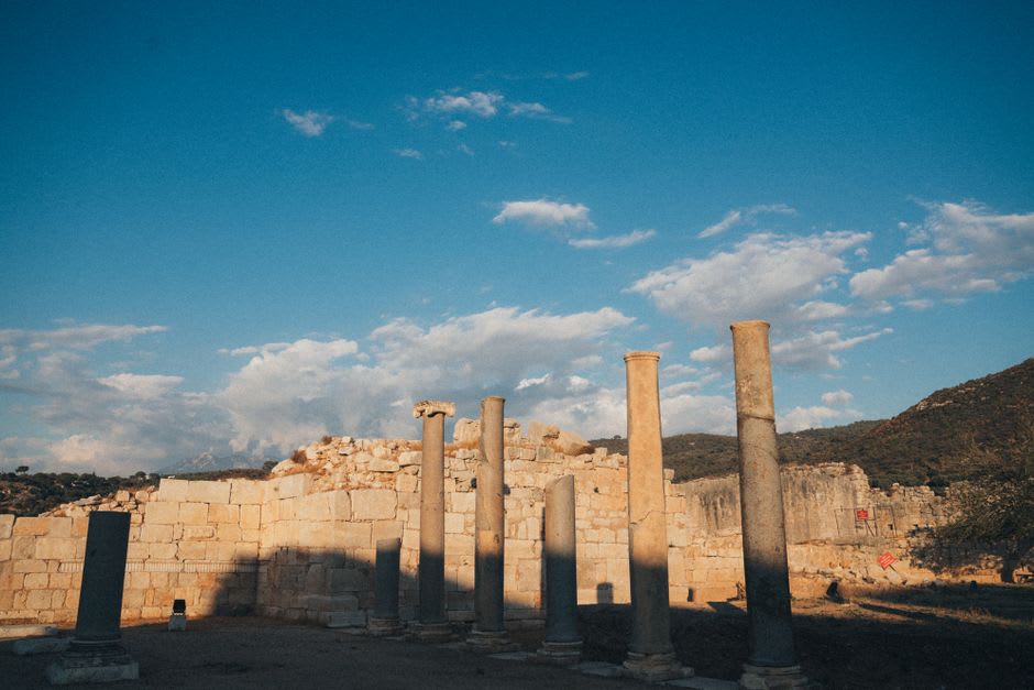 Sunlight cutting across a row of weathered stone columns at Hatra
