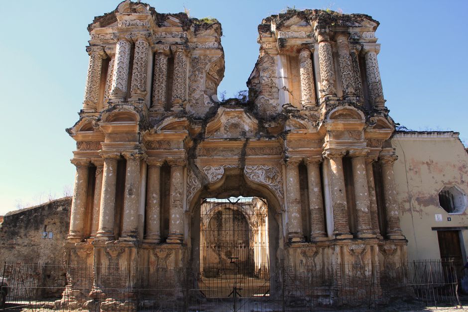 A partially destroyed temple facade at Hatra with visible damage from 2015, sunlight and shadow across the stone