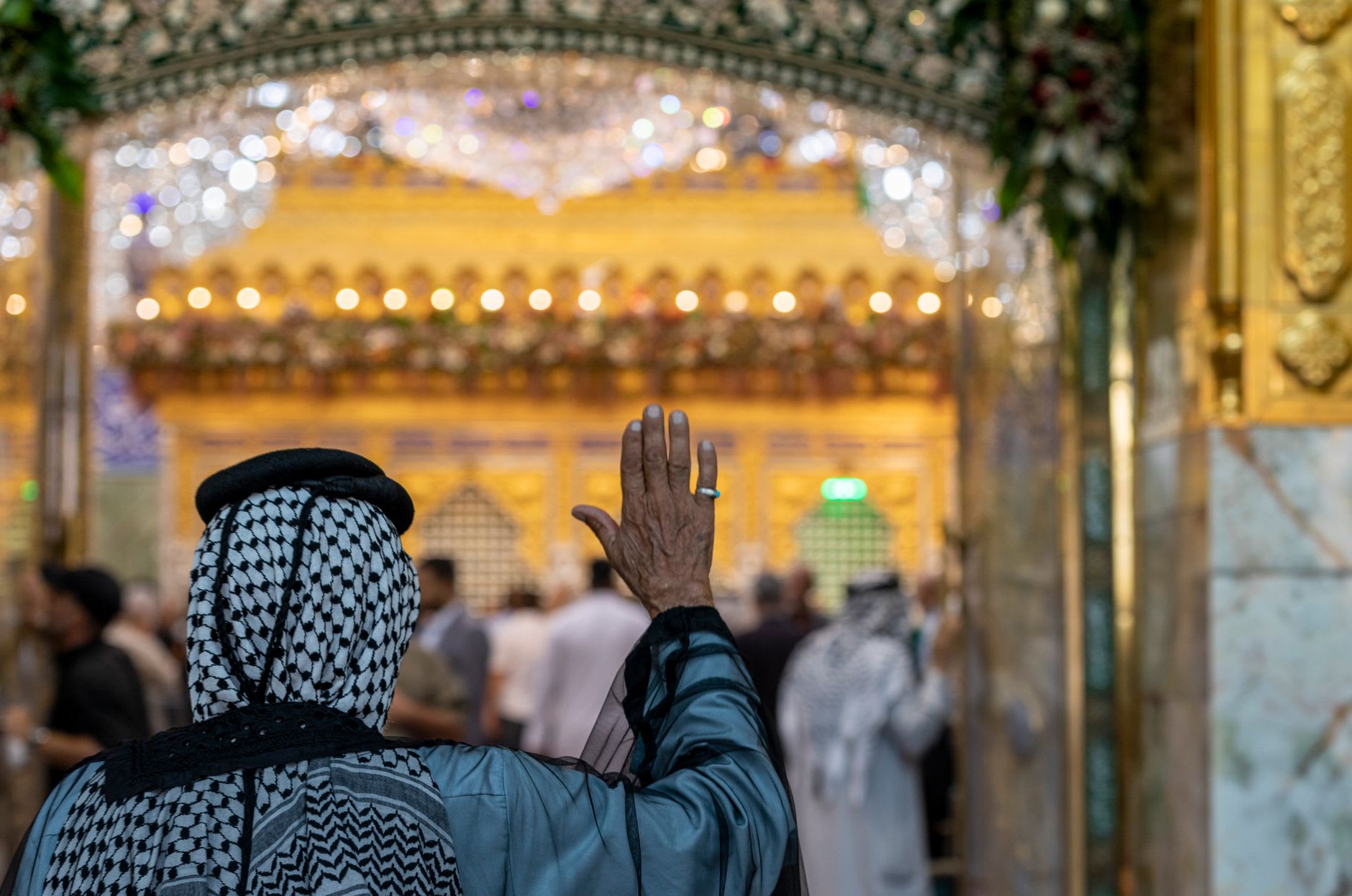 Peregrinos en oración en la explanada entre los dos santuarios gemelos de Kerbala, las cúpulas doradas elevándose a ambos lados a la luz de la mañana temprana