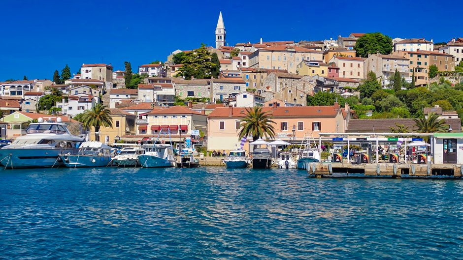 Small boats moored in Vrsar harbor with the old town rising behind