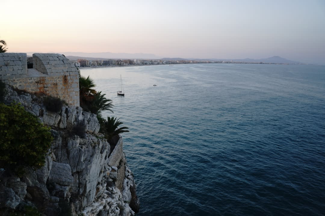 Alghero's fortified sea walls glowing gold at sunset with a lookout tower