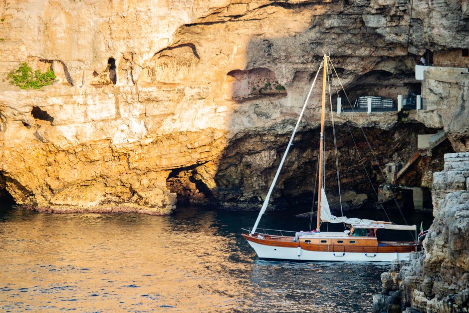 A small boat drifting near limestone sea caves along the Maratea coast