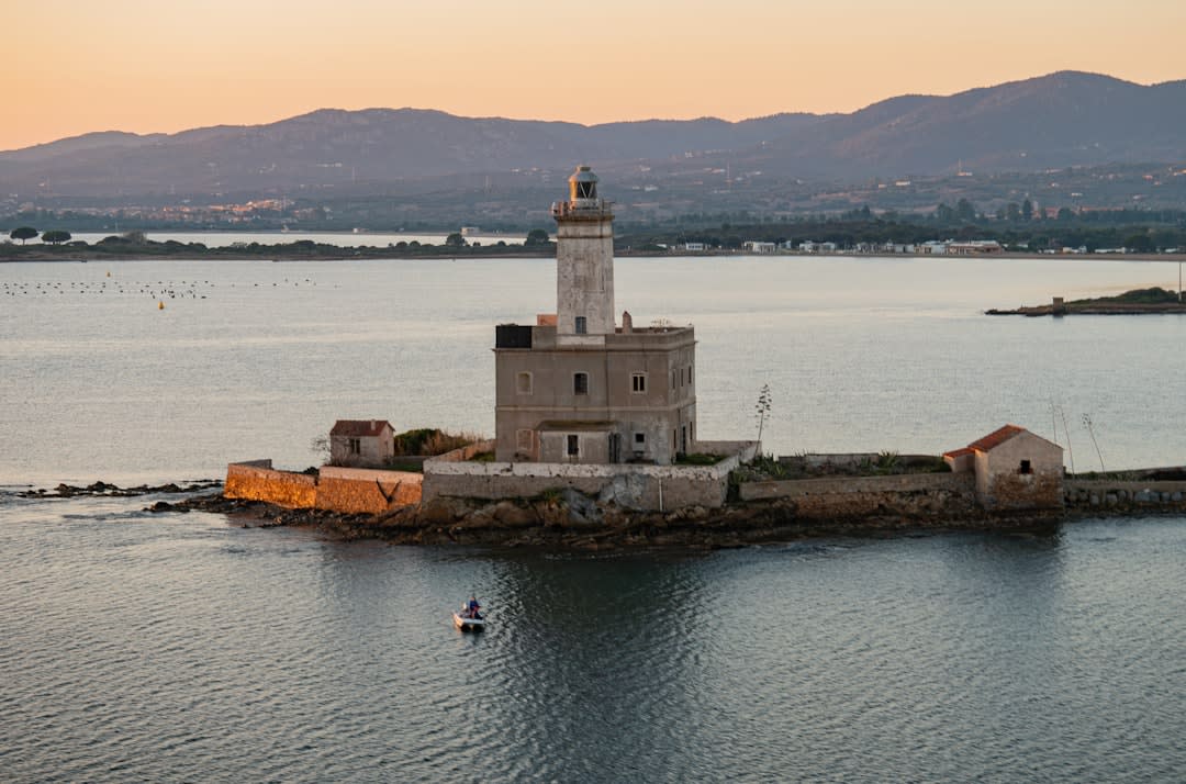 Fishing boats and the working harbor of Olbia at golden hour, with the old town rising behind