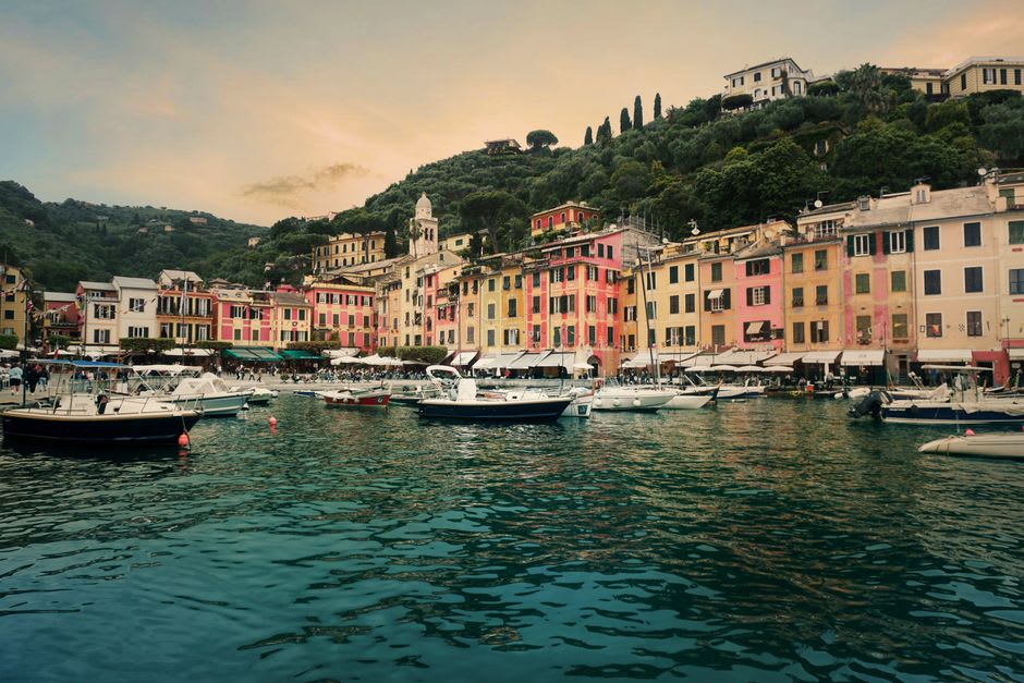Fishing boats and yachts anchored in Portofino's tiny natural harbor at sunset