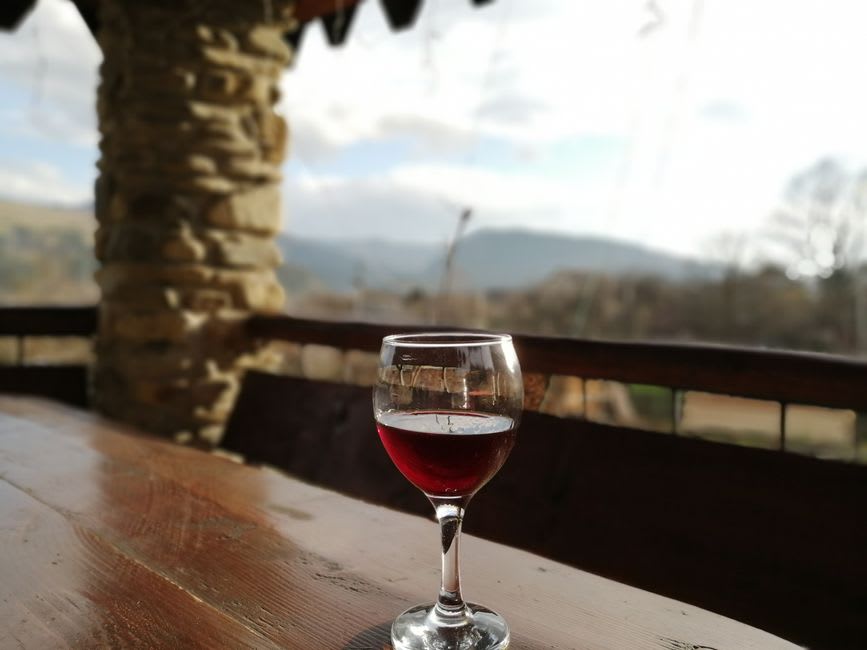 A glass of dark red Aglianico wine on a wooden table at a Potenza enoteca