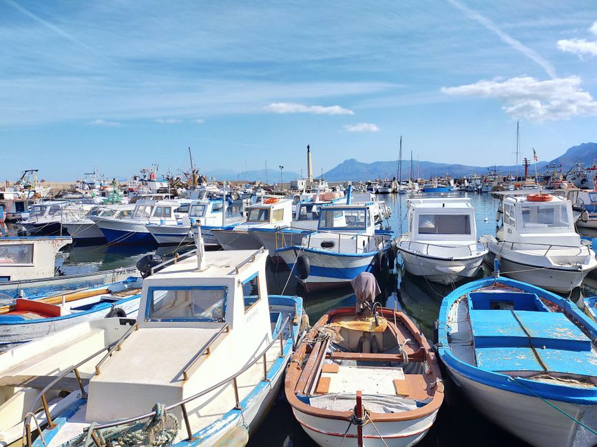 Fishing boats moored along Reggio Calabria's harbor at dusk with Sicily visible on the horizon