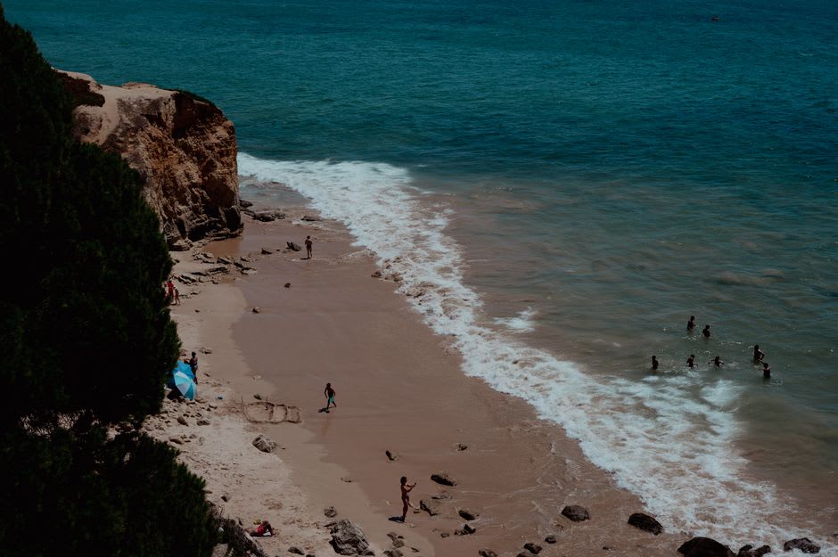 Swimmers and boats in the turquoise water below Tropea's cliffs