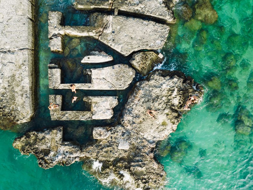 A small rocky cove along the Monopoli coastline in Puglia, with clear turquoise water between limestone outcrops