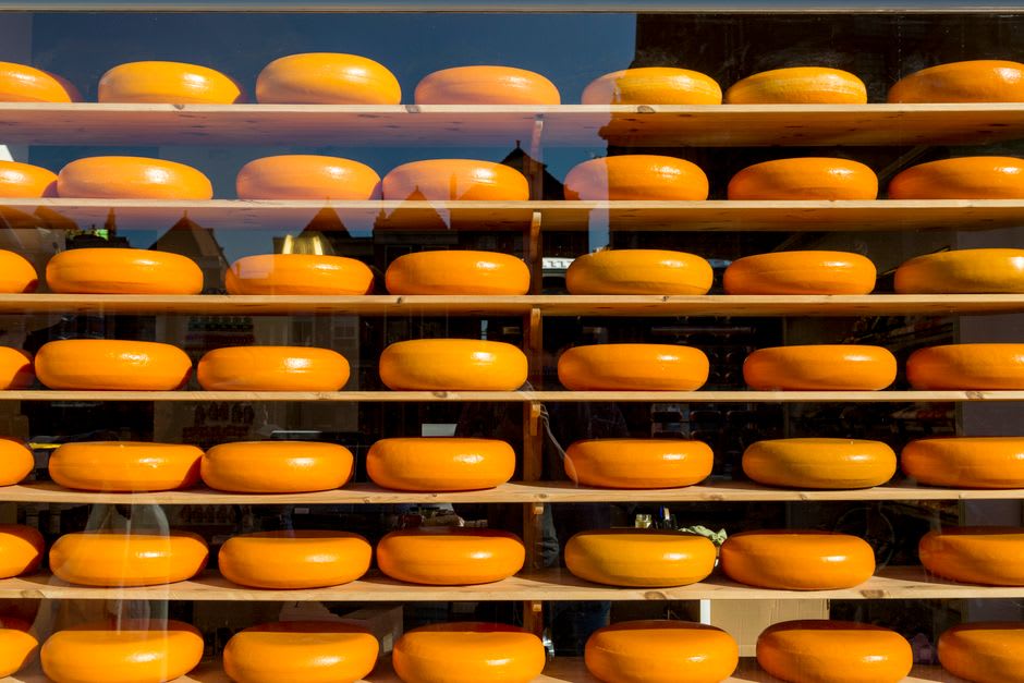 Rows of aging pecorino cheese wheels displayed in a Pienza shop window