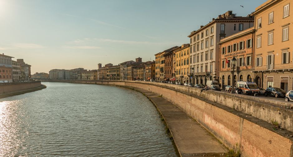 The Arno River lined with pastel-colored buildings in central Pisa