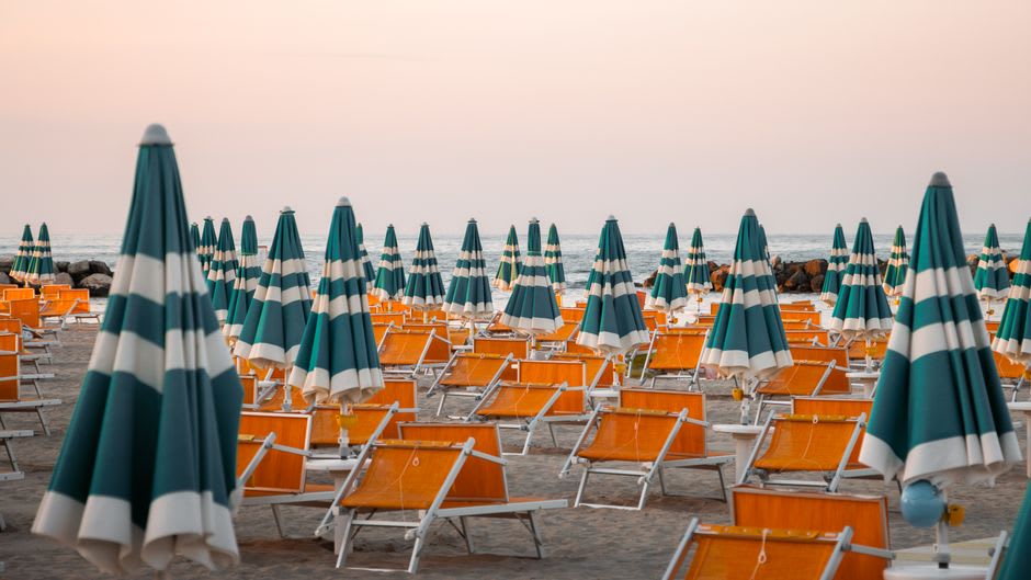 Rows of colorful beach umbrellas along the Rimini shoreline at sunset