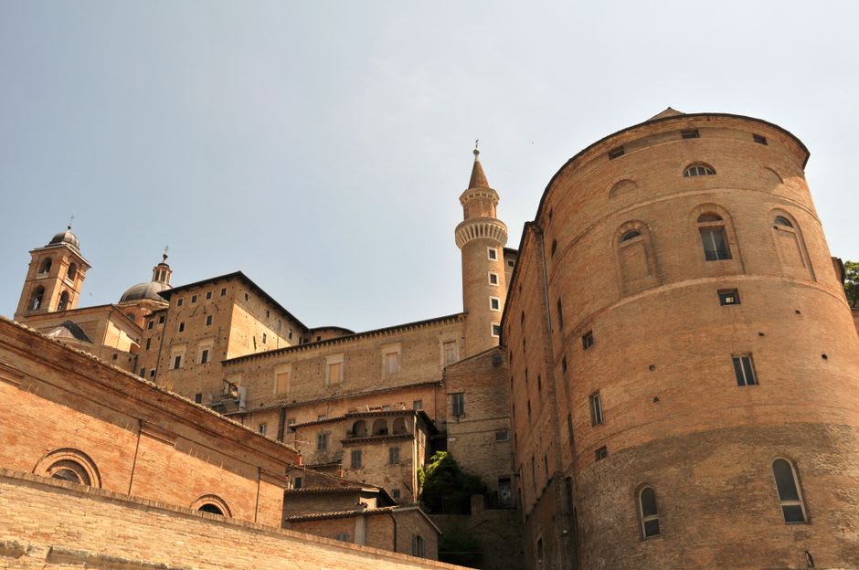 A narrow cobbled street in Urbino's historic center lined with terracotta buildings
